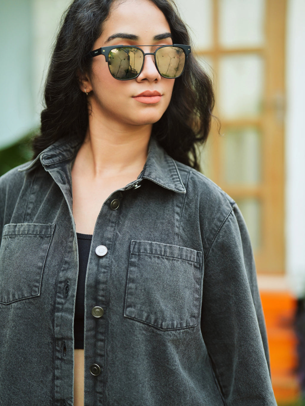 Woman wearing sunglasses and a denim jacket with a blurred background