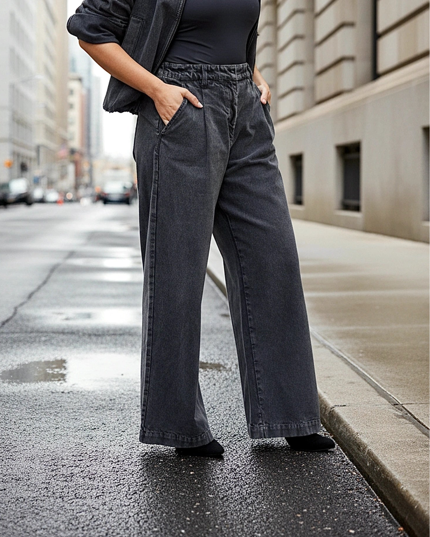 Person wearing dark gray wide-leg jeans on a city street.
