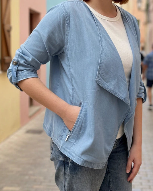 Person wearing a light blue denim jacket on a street.