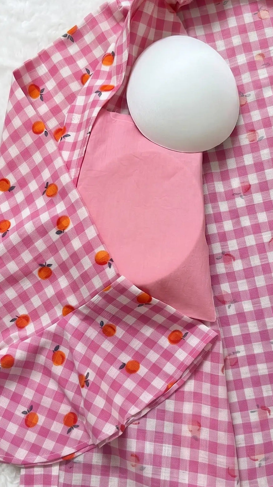Pink checkered garment with a white pad on a textured white background. Padded cotton night suit shirt for women. Removable pads. Pads not stiched. 