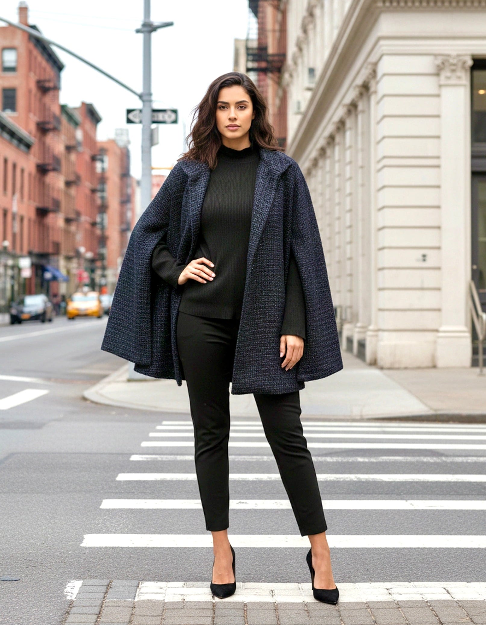 Woman in a navy coat and black outfit standing on a city street.